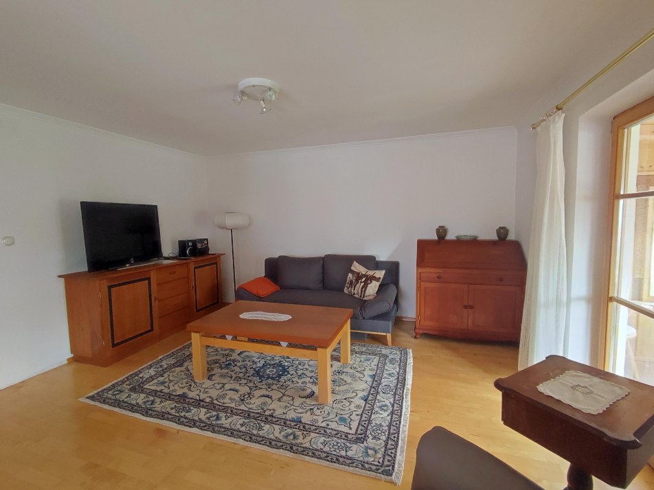 Wohnzimmer mit Schlafcouch & Tür zum Wintergarten