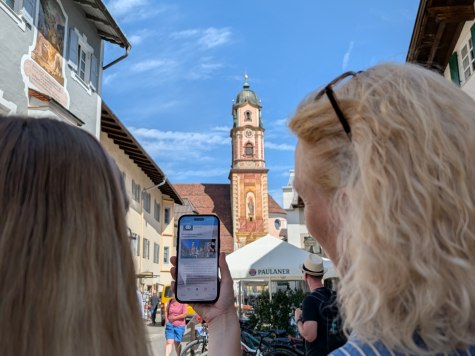 Innovative App mit Blick auf den Kirchturm Mittenwalds