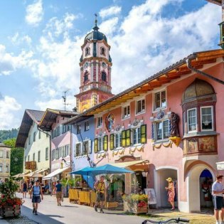 Blick in die bunte Hochstraße in Mittenwald auf Kirche St. Peter & Paul, © Alpenwelt Karwendel | mauritius images | Sina Ettmer | Alamy Blick in die bunte Hochstraße in Mittenwald auf Kirche St. Peter & Paul, © Alpenwelt Karwendel | mauritius images | Sina Ettmer | Alamy