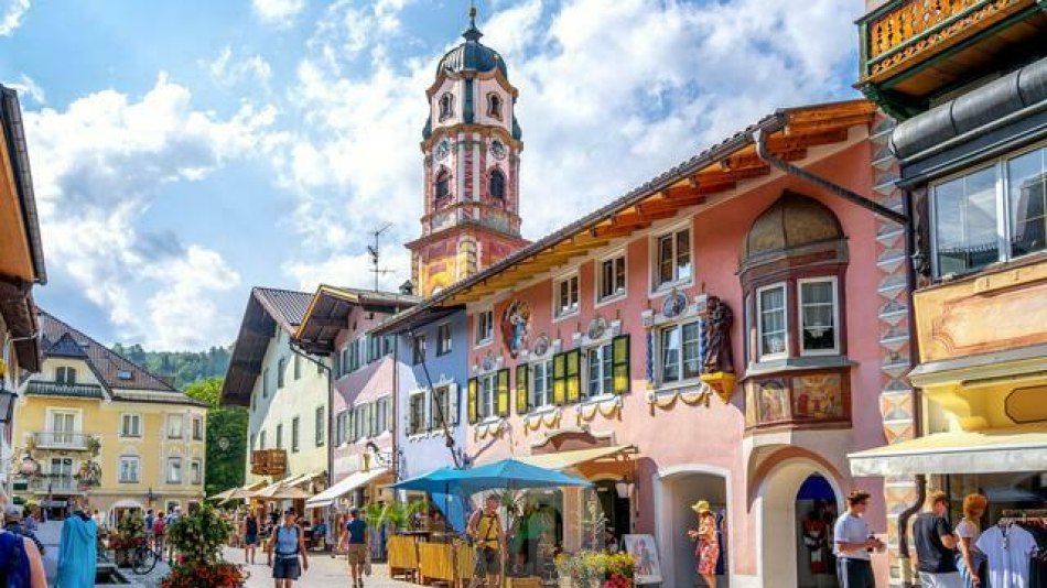 Blick in die bunte Hochstraße in Mittenwald auf Kirche St. Peter & Paul, © Alpenwelt Karwendel | mauritius images | Sina Ettmer | Alamy
