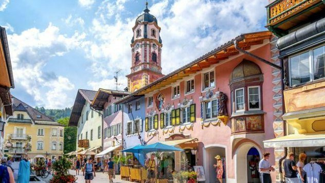 Blick in die bunte Hochstraße in Mittenwald auf Kirche St. Peter & Paul, © Alpenwelt Karwendel | mauritius images | Sina Ettmer | Alamy