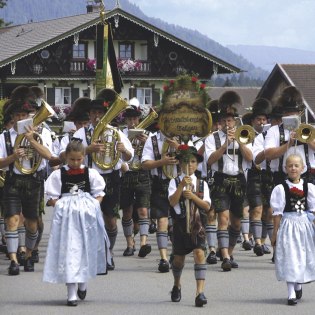 Musikkapelle Wallgau in typisch bayerischert Tracht, im Vordergrund der "Dafalabua" Franzi., © Alpenwelt Karwendel | Hubert Hornsteiner