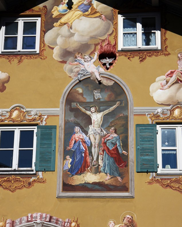 Lüftlmalerei auf einem Haus in Mittenwald mit Jesus am Kreuz in einer Passionsdarstellung. , © Alpenwelt Karwendel | Rudolf Pohmann