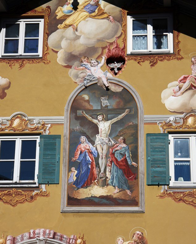 Fresco painting on a house in Mittenwald with Jesus on the cross in a passion representation. , © Alpenwelt Karwendel | Rudolf Pohmann