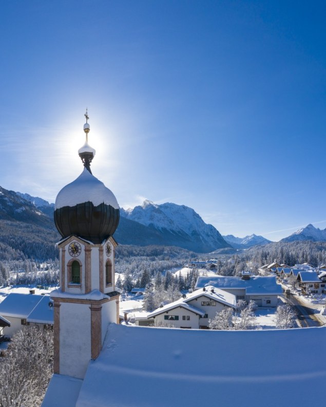 Winter in Krün - Kirchturm mit Bergpanorama von Seinskopf bis Waxensteine., © Alpenwelt Karwendel | Kriner & Weiermann