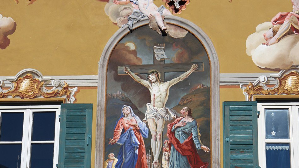 Fresco painting on a house in Mittenwald with Jesus on the cross in a passion representation. , © Alpenwelt Karwendel | Rudolf Pohmann