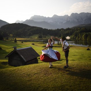 Ein Plattlerpaar aus Krün vor Geroldsee und Karwendelmassiv, © Alpenwelt Karwendel | Philipp Gülland