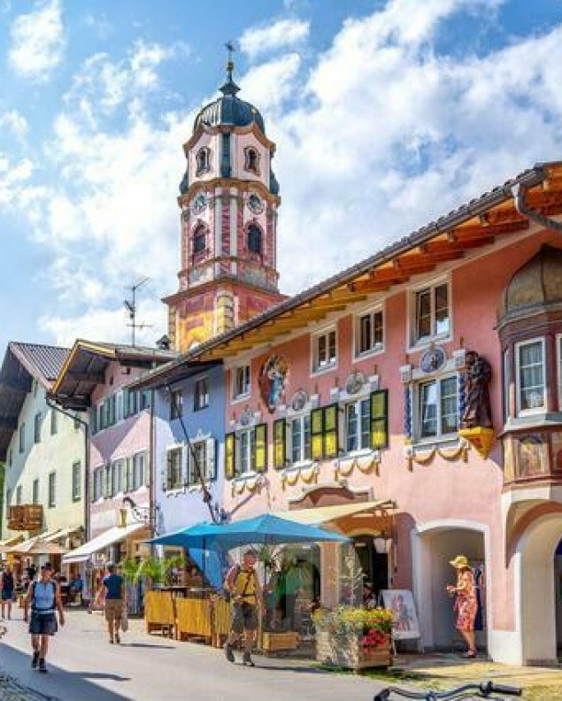 Blick in die bunte Hochstraße in Mittenwald auf Kirche St. Peter & Paul, © Alpenwelt Karwendel | mauritius images | Sina Ettmer | Alamy