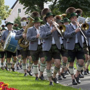 Die Mittenwalder Musikkapelle bei einem sommerlichen Umzug. Blasmusik mit Trommlerzug in Trachten. , © Alpenwelt Karwendel | Hubert Hornsteiner