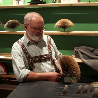 Der Gamsbart, im Isartal besonders prächtig! Hier gezeigt von Gamsbartbinder Hans Schober, der auch bei der Gamsbart-Olympiade immer mitten drin ist., © Alpenwelt Karwendel | Christoph Schober