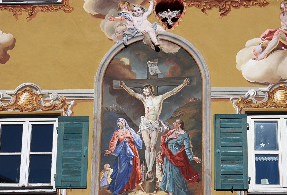 Lüftlmalerei auf einem Haus in Mittenwald mit Jesus am Kreuz in einer Passionsdarstellung. , © Alpenwelt Karwendel | Rudolf Pohmann