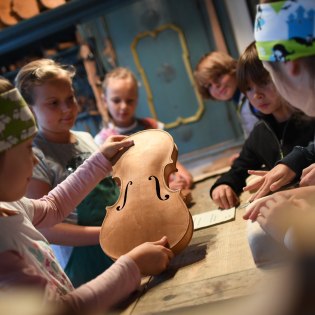 Children with violin in the violin making museum - children's program, © Alpenwelt Karwendel | Angelika Warmuth